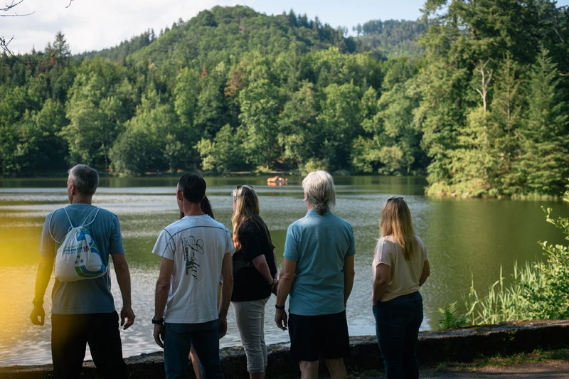 Gruppe von Menschen stehen am see und schauen aus wasser