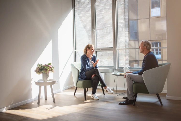Frau und Mann sitzen vor einem Fenster und unterhalten sich