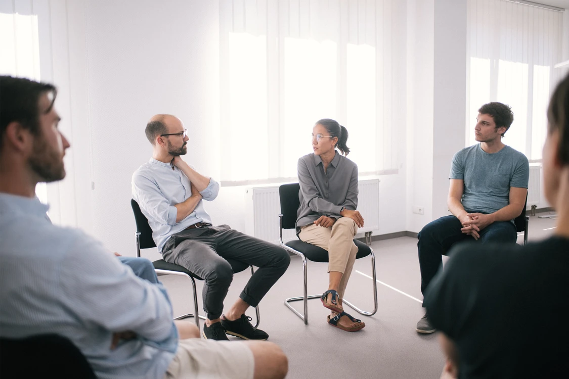 gruppe sitzt in einem wei&szlig;en raum und redet