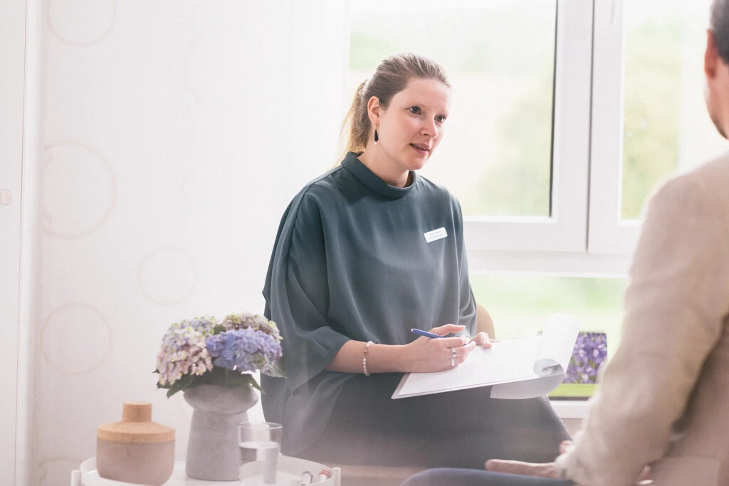 Frau spricht mit Patient und macht notizen